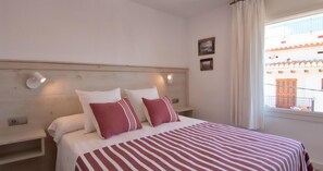 Ein Bett mit gestreifter Bettdecke, zwei Kissen und Wandleuchten zum Lesen.