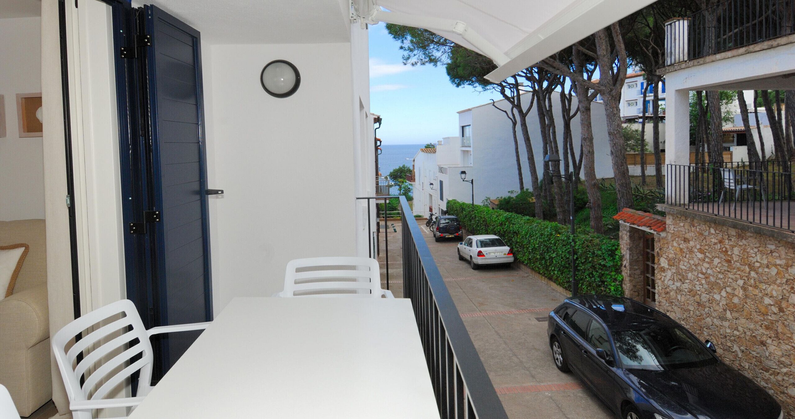 Un balcon avec une table et des chaises, une vue sur la rue et une horloge au mur.