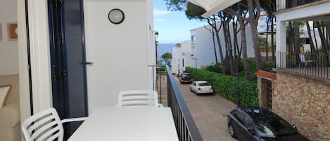 Un balcon avec une table et des chaises, une vue sur la rue et une horloge au mur.