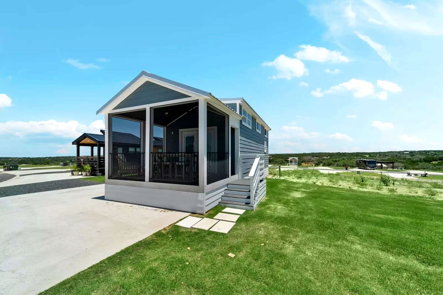 Een klein, gelijkvloers huis met een veranda, een overdekt zitgedeelte en een gazon.