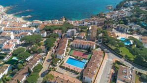 Ett flygbildsfoto av ett bostadsområde vid kusten med hus, en strand och en stor swimmingpool.