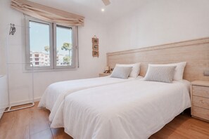 Ein Schlafzimmer mit zwei Einzelbetten, einem Holzkopfstück, einem Nachttisch und einem Fenster mit Vorhängen.