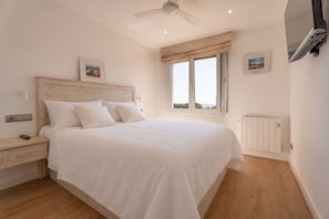 A bedroom with a bed, nightstand, and a window with a view. - Renovated flat with sea views and a swimming pool · 150 metres from the beach · Calella (Calella de Palafrugell)
