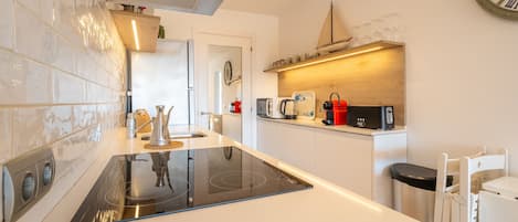 A modern kitchen with a central island, built-in appliances, and a clock on the wall.
