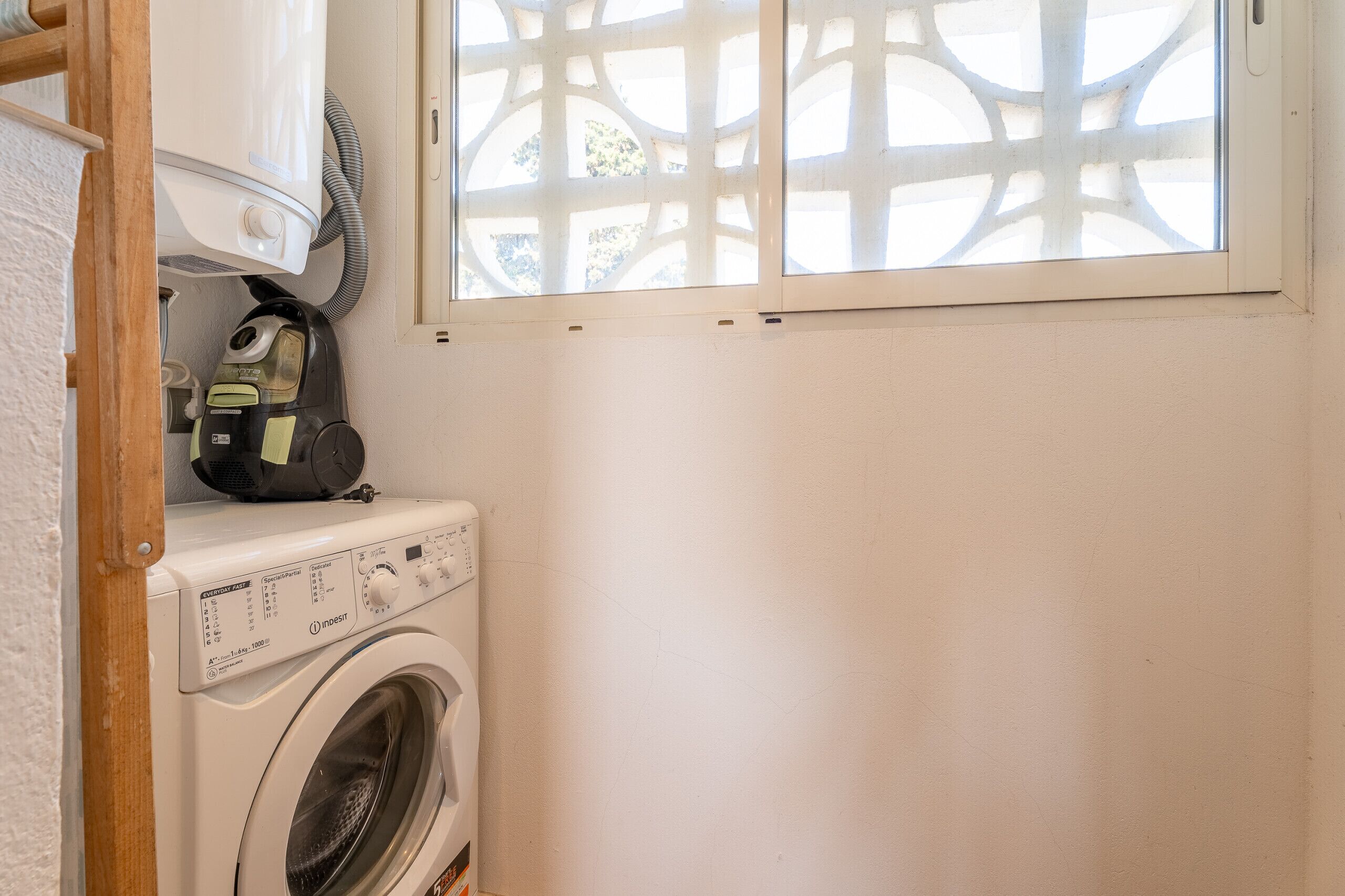 Een kleine wasruimte met een voorlader wasmachine en een stoomstrijkijzer op het aanrecht.