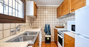 Een moderne keuken met een dubbele spoelbak, houten kastjes, een magnetron en een fornuis.