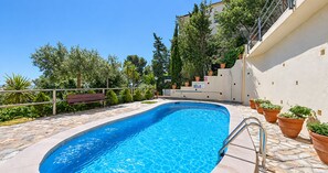 A swimming pool with a stone deck, surrounded by potted plants and a metal fence. - Apartment with Beautiful Sea Views and Pool in Calella · Perfect to Relax (Calella de Palafrugell)