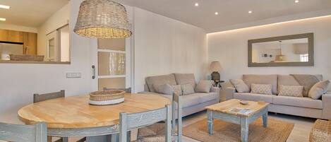 Una sala moderna con una mesa de comedor redonda de madera, un sofá y una mesa auxiliar.