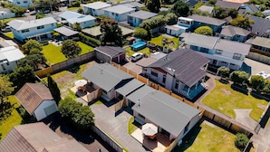 Vista aérea de una zona residencial con varias casas, una casa central con patio y un jardín cercado.