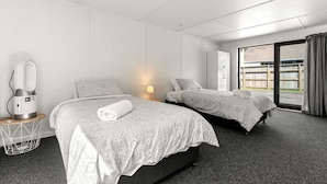 Habitación de hotel con dos camas, un escritorio con lámpara, secador de pelo y vistas al exterior.