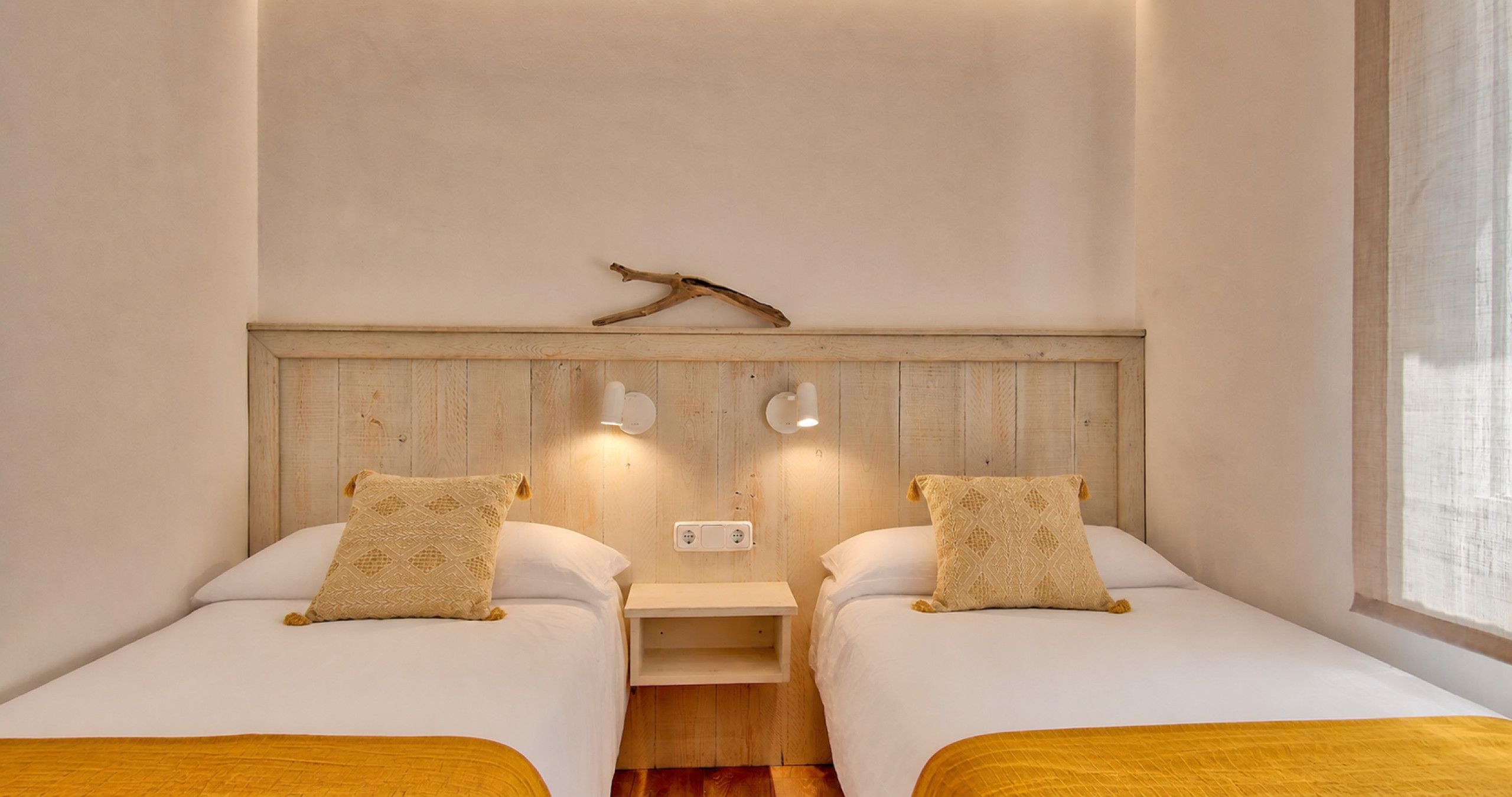 A room with two beds, each with a matching pillow and a small bedside table.