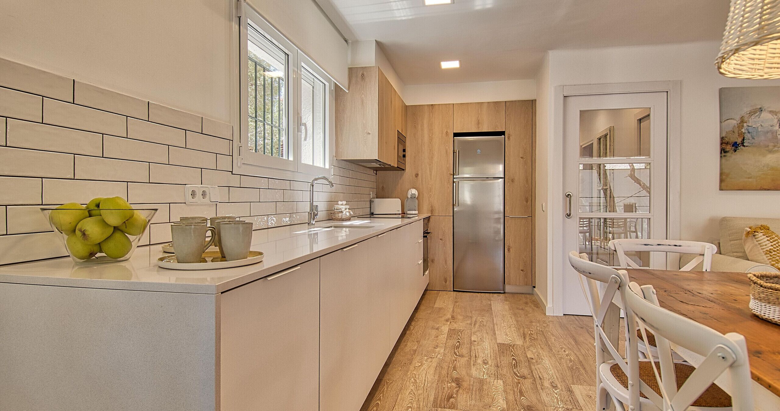 Una cucina moderna con isola integrata, elettrodomestici in acciaio inox e pavimento in legno.