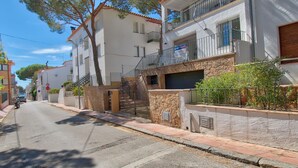 A residential street with multi-story buildings, a gated entrance, and a clear sky. - Elegant apartment 100m from the beach with parking and air conditioning (Llafranc)