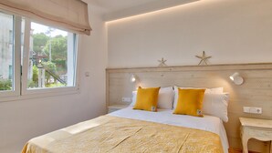 A bedroom with a bed, two bedside lamps, a nightstand, and a window with curtains. - Elegant apartment 100m from the beach with parking and air conditioning (Llafranc)