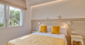 Ein Schlafzimmer mit einem Bett, zwei Nachttischlampen, einem Nachttisch und einem Fenster mit Vorhängen.