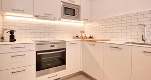 Eine moderne Küche mit weißen Schränken, einem eingebauten Ofen, einer Mikrowelle und einer Holz Arbeitsplatte.