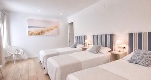 A hotel room with two beds, a chair, and a painting on the wall. - Ground floor 50 meters from the beach (Calella de Palafrugell)