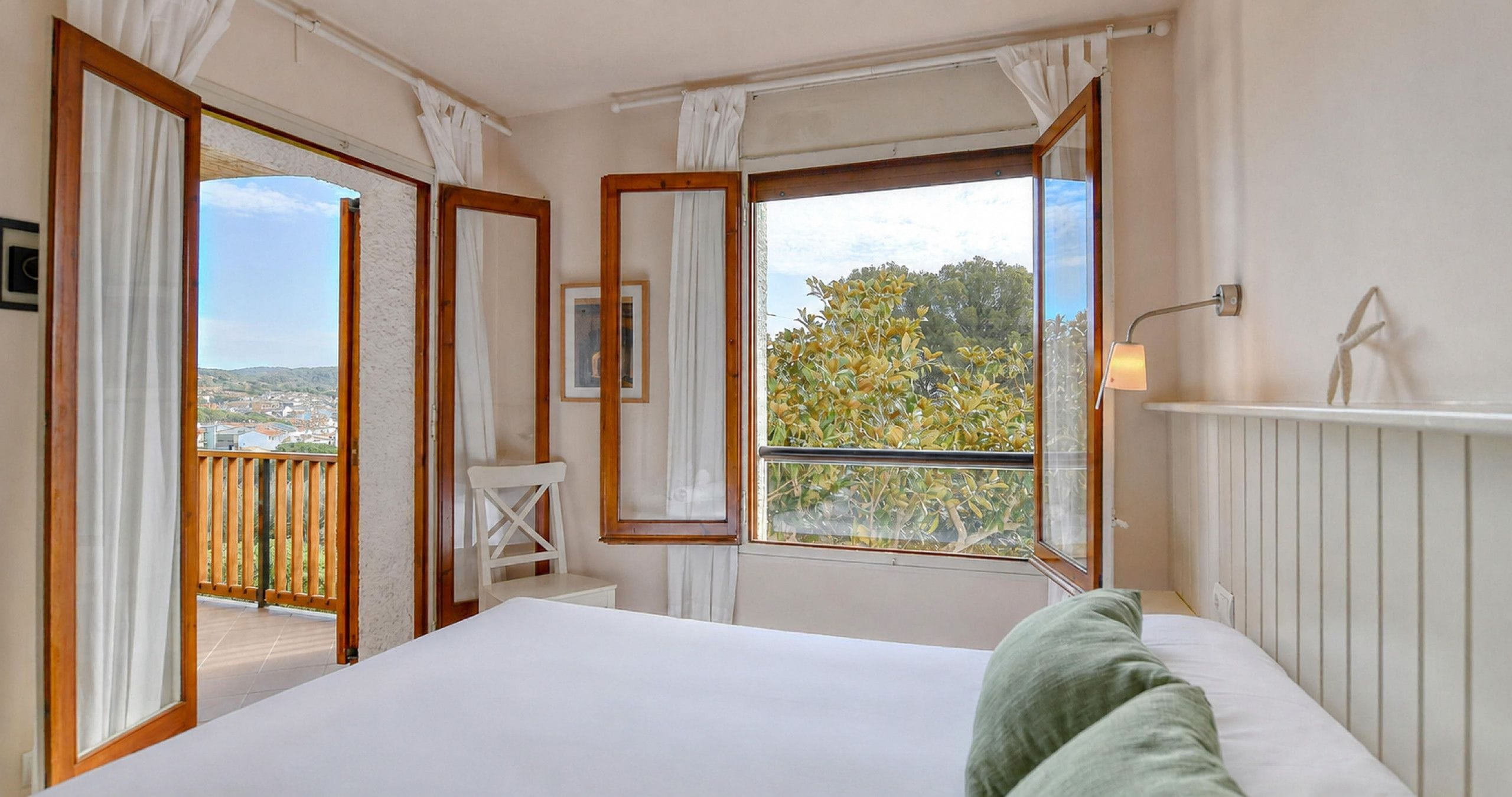 A bedroom with a large bed, a view of the outdoors, and a balcony.