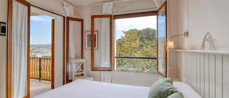 A bedroom with a large bed, a view of the outdoors, and a balcony.