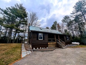 A small cabin with a porch, a staircase, and a gravel driveway. - Waterfront Cabin Retreat with Deck Swing in Lamoine Point, Maine (Lamoine Point)