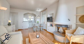 Ein modernes Wohnzimmer mit Kamin, Essbereich und einer Küche im Hintergrund.