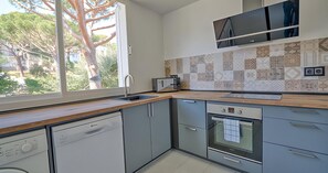 Eine moderne Küche mit Geschirrspüler, Backofen und einem großen Fenster.
