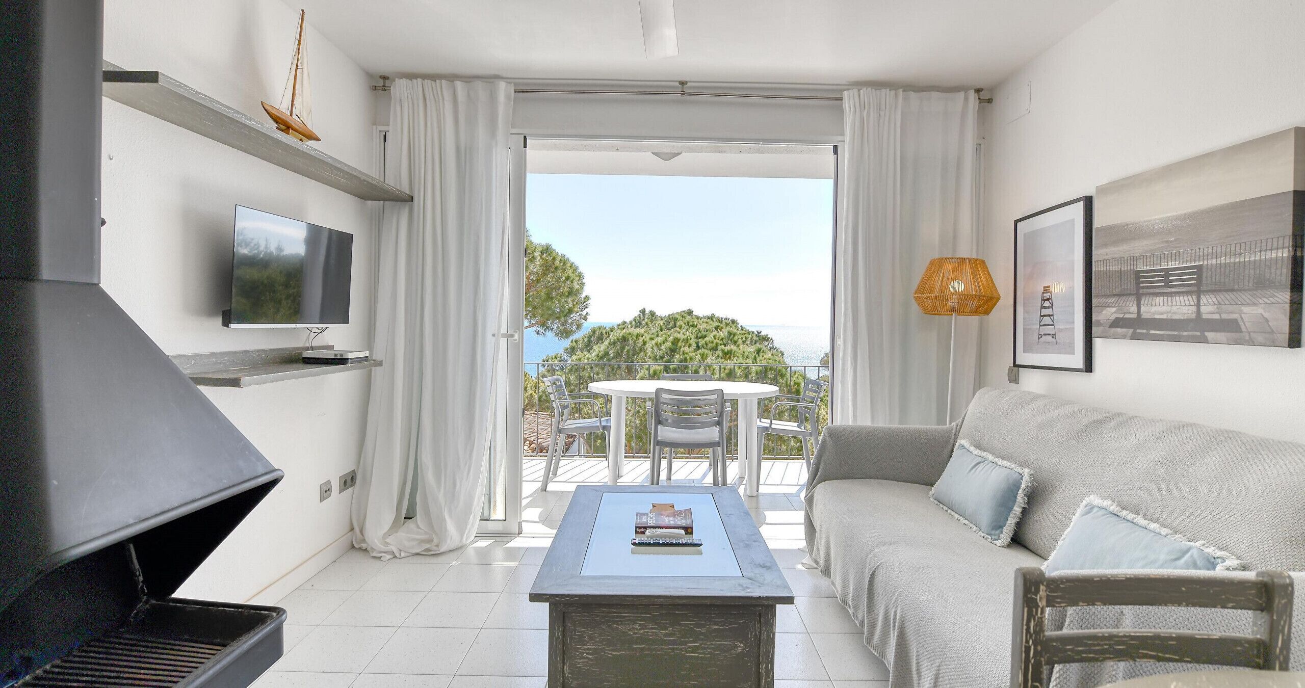 Un salon moderne comprenant un téléviseur, un barbecue, un canapé et un coin repas avec une table et des chaises.