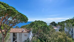 A coastal property with a white building, a red-tiled roof, and a view of the sea. - Sea View Apartment in Calella with Parking Included (Calella de Palafrugell)