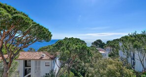 Ein Küstengebiet mit einem weißen Gebäude, einem roten Ziegeldach und Blick auf das Meer.