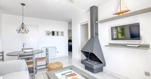 Ein modernes Wohnzimmer mit Kamin, Essbereich und Wand-Fernseher.
