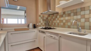Een moderne keuken met een gasfornuis, vaatwasser en een spoelbak.