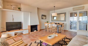 A living room with a TV, fireplace, dining table, chairs, and a sofa. - Charming beachfront apartment with sea views just 10 meters from the beach in Cala de Calau, Calella de Palafrugell. (Calella de Palafrugell)