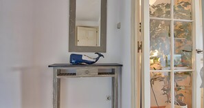 A room with a white door, a mirror above a console table, and a blue object on the table. - Charming beachfront apartment with sea views just 10 meters from the beach in Cala de Calau, Calella de Palafrugell. (Calella de Palafrugell)