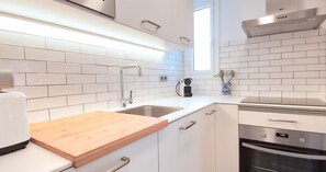 A modern kitchen with white subway tiles, stainless steel appliances, and a wooden countertop. - Renovated accommodation with air conditioning (Calella de Palafrugell)