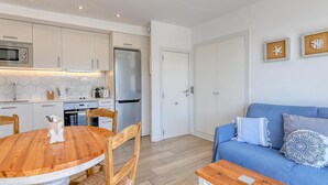A modern kitchen with white cabinets, a stainless steel refrigerator, and a wooden dining table with chairs. - Studio with sea views in the center of Calella (Calella de Palafrugell)