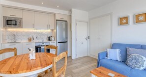 A modern kitchen with white cabinets, a stainless steel refrigerator, and a wooden dining table with chairs. - Studio with sea views in the center of Calella (Calella de Palafrugell)