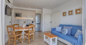 A compact living space with a dining area, kitchenette, and a blue sofa with decorative pillows. - Studio with sea views in the center of Calella (Calella de Palafrugell)