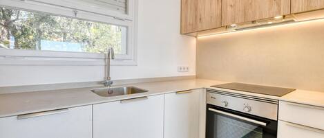 A modern kitchen with a sink, oven, and wooden cabinets.