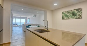 Eine moderne Küche mit Kochinsel, einem Essbereich mit Stühlen und einem großen Fenster.