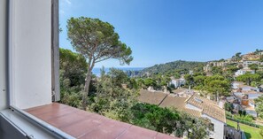 A balcony with a view of a coastal town, including houses and a prominent tree. - Spectacular and spacious penthouse with communal pool in the Golfet area (Calella de Palafrugell)