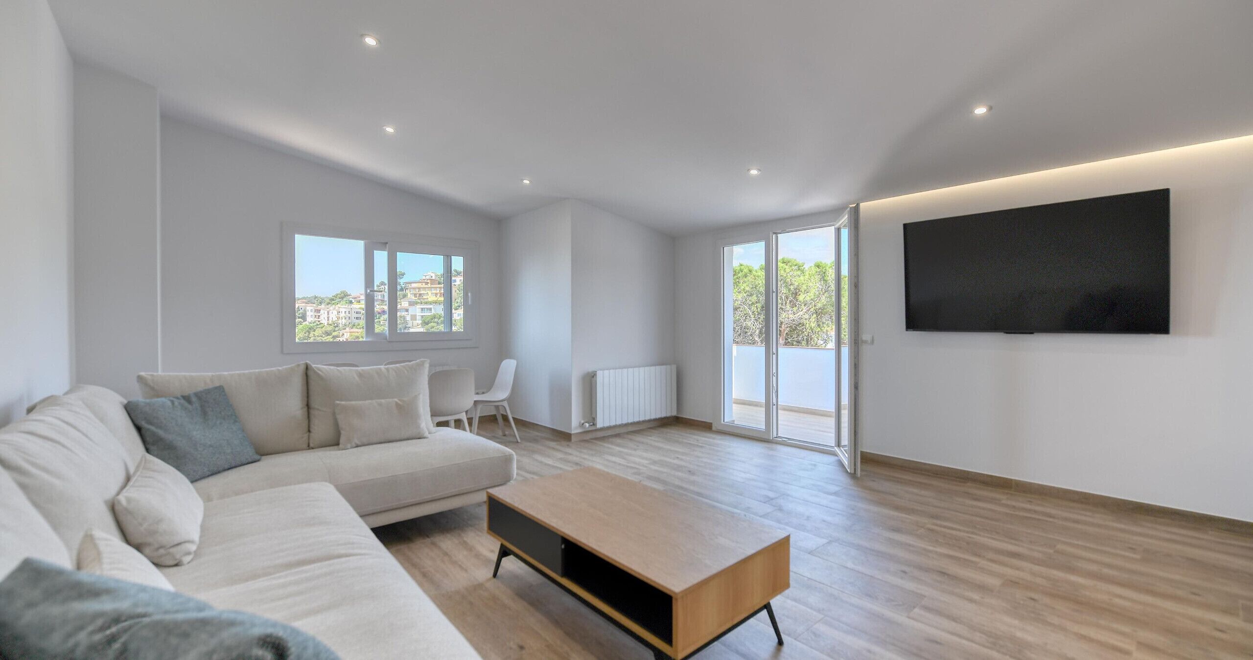 A modern living room with a sofa, a coffee table, and a TV mounted on the wall.