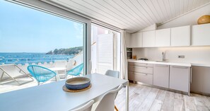 A modern kitchen with white cabinets and a view of the sea. - Charming beachfront apartment with sea views just 10 meters from the beach in Cala del Calau, Calella de Palafrugell (Calella de Palafrugell)