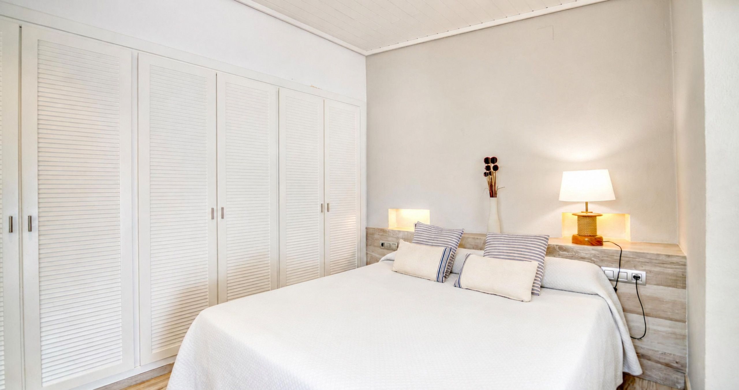 Une chambre à coucher avec un lit, des lampes de chevet, une guitare et une armoire.