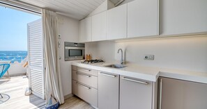 A modern kitchen with a built-in oven, microwave, and stainless steel sink. - Charming beachfront apartment with sea views just 10 meters from the beach in Cala del Calau, Calella de Palafrugell (Calella de Palafrugell)