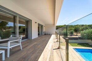 A modern outdoor balcony with a pool, white furniture, and a clear view of the surrounding greenery. - Modern chalet with private pool (Calella de Palafrugell)