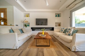 Ein modernes Wohnzimmer mit zwei Sofas, einem Couchtisch, einem Flachbildfernseher und Dekorationen auf Regalen.