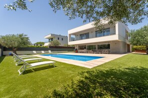 A modern two-story house with a swimming pool, outdoor seating, and a well-maintained lawn. - Modern chalet with private pool (Calella de Palafrugell)