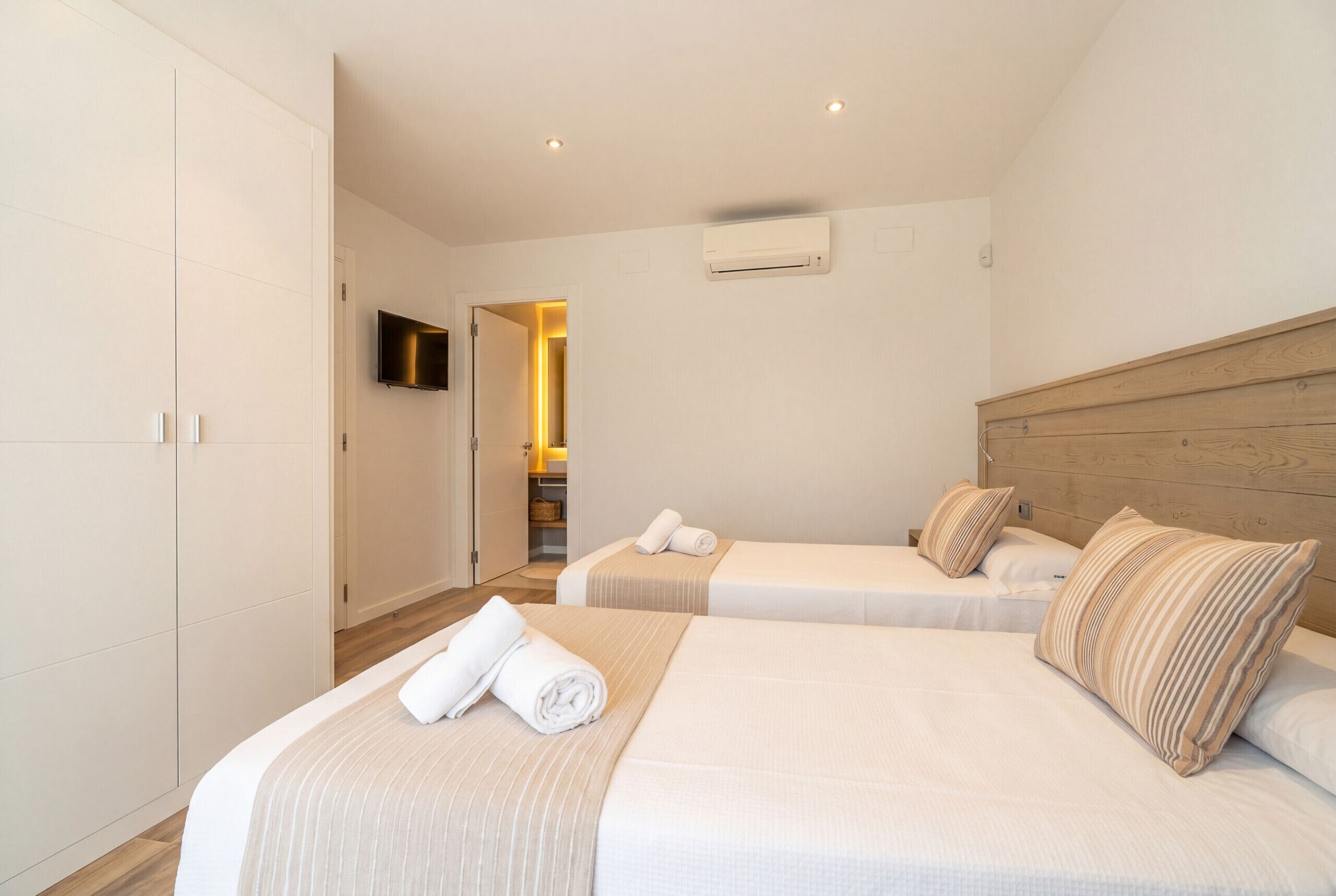 Ein Hotelzimmer mit zwei Betten, einem Fernseher und einer Klimaanlage.