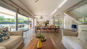 A spacious living area with a dining table, sofas, and a large window overlooking a garden. - Modern chalet with private pool (Calella de Palafrugell)