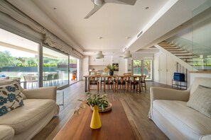Ein geräumiger Wohnbereich mit Esstisch, Sofas und einem großen Fenster mit Blick auf einen Garten.